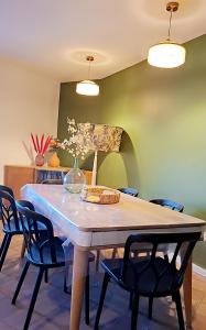 a dining room table with chairs and a vase of flowers at Maison Pivoines in Saint-Martin-dʼArdèche