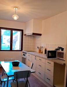 a small kitchen with a table and a microwave at Maison Pivoines in Saint-Martin-dʼArdèche