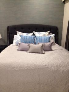 a large bed with a black headboard and many pillows at By the Sea PENTHOUSE duplex in Batu Ferringhi