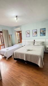 two beds in a bedroom with wooden floors at Residencial Amora in Canela