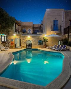 a large swimming pool with blue water at night at Ta' Ġilarda Boutique Living in Birbuba