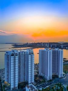 a group of tall white buildings in front of a sunset at Sapphire House Hạ Long in Ha Long