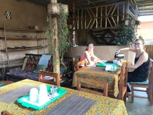 two people sitting at tables in a restaurant at OM Hostel Bunyonyi in Kabale