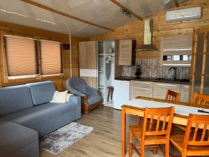 a living room with a couch and a table and a kitchen at Domki Letniskowe ARTEMI in Rowy