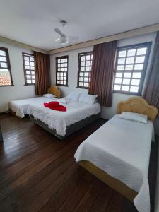 two beds in a room with two windows at Pousada Flor de Lis in Diamantina