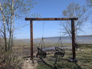 two chairs on a swing in front of the water at Condo 1 - Waterfront with SPA Fireplace & Barbecue in Sainte-Anne-de-Beaupré