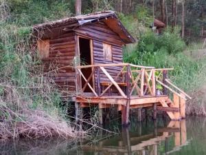 a log cabin on the water with a bridge at OM Hostel Bunyonyi in Kabale