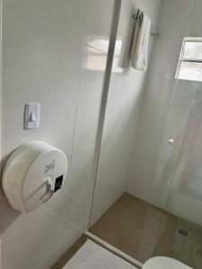 a shower with a glass door next to a toilet at Della Economy Hotel in Paranaguá