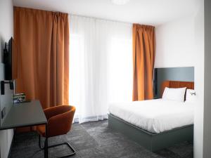 a bedroom with a bed and a desk with a computer at B&B HOTEL Leszno in Leszno
