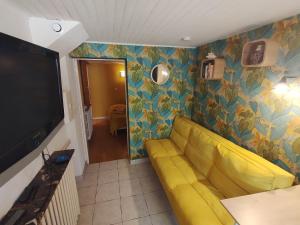 a living room with a yellow couch and a tv at Studio Athena in Aix-les-Bains