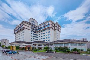 um grande edifício com um carro estacionado num parque de estacionamento em Zhangjiajie International Hotel em Zhangjiajie
