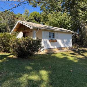 a white house with a window in a yard at Chalé da Araucária in Campos do Jordão +12 photos