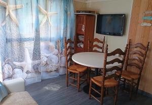 a room with a table and chairs and a tv at CHALET Les ALGUES in Plobannalec-Lesconil