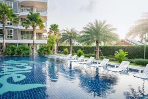 a swimming pool with white chairs and a building at NEW amazing studio a private marina in Na Jomtien