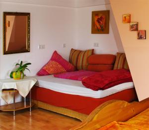 a bedroom with a bed with red and pink pillows at Gasthaus Korfu in Edenkoben