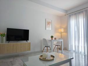 a white living room with a tv and a table at Living Sevilla & Parking gratis in Seville