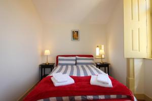 Un dormitorio con una cama roja con toallas. en Casa 11 Cravos by LovelyStay, en Figueira da Foz