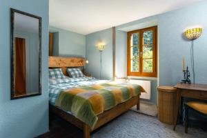 a bedroom with a bed and a desk and a mirror at Heidi's Guesthouse in Frenières