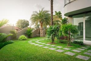 a garden with palm trees next to a building at Beautiful studio by the beach with private marina in Na Jomtien