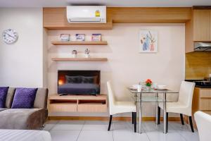 a living room with a couch and a table with a television at Beautiful studio by the beach with private marina in Na Jomtien