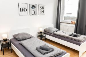 Dos camas en una habitación blanca con ventana. en CosyHomes24 - Centrally with balcony and parking space - MH06, en Mülheim an der Ruhr