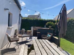 a patio with a wooden table and chairs and an umbrella at KER NALA - Jolie maison familiale pour 5 vacanciers in Plouharnel