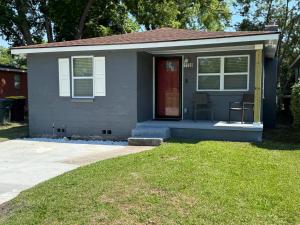 a small house with a red door and a lawn at Mae's Place in Savannah