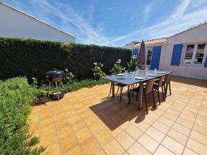 a patio with a table and chairs and a grill at Maison familiale à Barbâtre face à la dune, 3 chb, 2 SDB, 8 personnes in Barbâtre