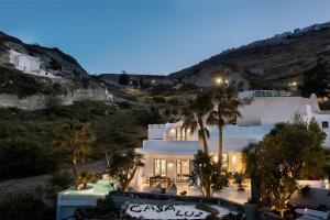 a large white building with palm trees in front of a hill at Casa Luz in Pyrgos
