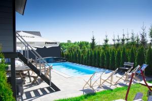 a swimming pool with a table and chairs next to a house at Anetta Domki Mielno in Mielno