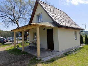 a small white house with a wooden roof at Przy wodzie - Jacnia in Jacnia