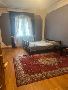 a bedroom with a bed and a rug and a window at La villa de Ramil in Baku