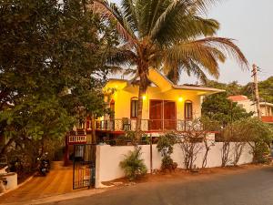 a yellow house with a palm tree in front of it at Peaceful Studios in Assagao in Parra