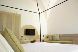 sypialnia z łóżkiem, kanapą i telewizorem w obiekcie Masseria Don Luigi-Luxury Farmhouse w mieście Savelletri di Fasano +37 zdjęć