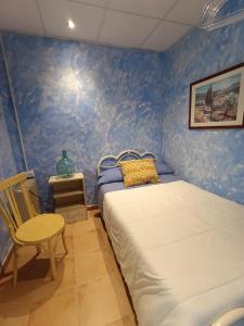 ein blaues Schlafzimmer mit einem Bett und einem Stuhl in der Unterkunft Casa Rural El Patio in Valmuel