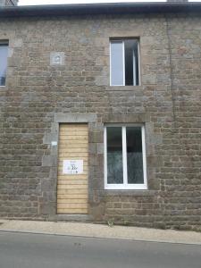 a brick building with a door with a sign on it at Gîte du Roc 1 in Les Portes du Coglais +4 photos