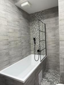 a bath tub in a bathroom with a tile wall at Karlovy Vary Cute in Karlovy Vary