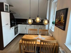 a kitchen with a wooden table and some lights at Kiebitznest in Krummhörn +10 photos
