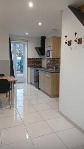 eine Küche mit weißem Fliesenboden und einem Tisch in der Unterkunft Gîte du Roc 2 in Les Portes du Coglais