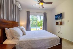 a bedroom with a bed with a ceiling fan and a window at Beachfront Cabarete Apartment in Cabarete +36 photos