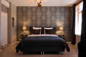 a bedroom with a bed and a wall with a chandelier at B&B De Koepoort in Mechelen