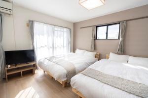 two beds in a room with a tv and a bedroom at Alpha memory NAGOYA in Mutsunochō