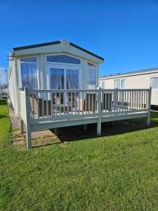 a blue house with a porch on the grass at Lbn Caravan in Kinmel Bay