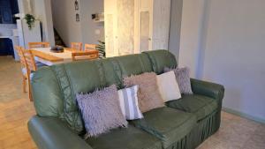 a green leather couch with purple and white pillows on it at Rincon de la Araucaria Dina Huapi in Dina Huapi