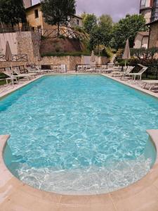 "Tuscany Hill" con giardino privato e piscina في Castagno: تجمع كبير من الماء الأزرق مع الكراسي والمظلات