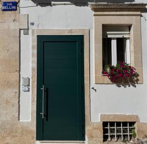 una porta verde su un edificio con finestra di Volta Meraviglia a Martina Franca