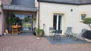 a patio with chairs and a table in front of a house at Le coup de foudre in Le Molay-Littry