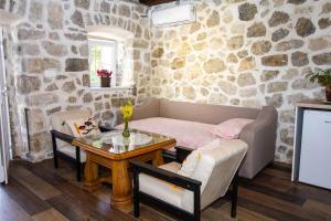 a living room with a table and a stone wall at Apartmani Stone oasis in Zupci