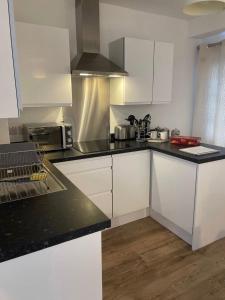 a kitchen with white cabinets and black counter tops at Modern studio in popular South Kensington location in London