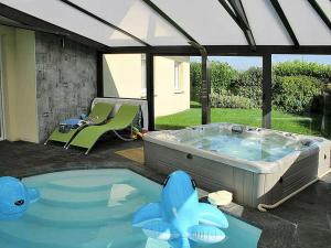 duża wanna z hydromasażem na patio ze stołem i krzesłem w obiekcie Bretagne,maison avec piscine et spa w mieście Kersaint-Plabennec